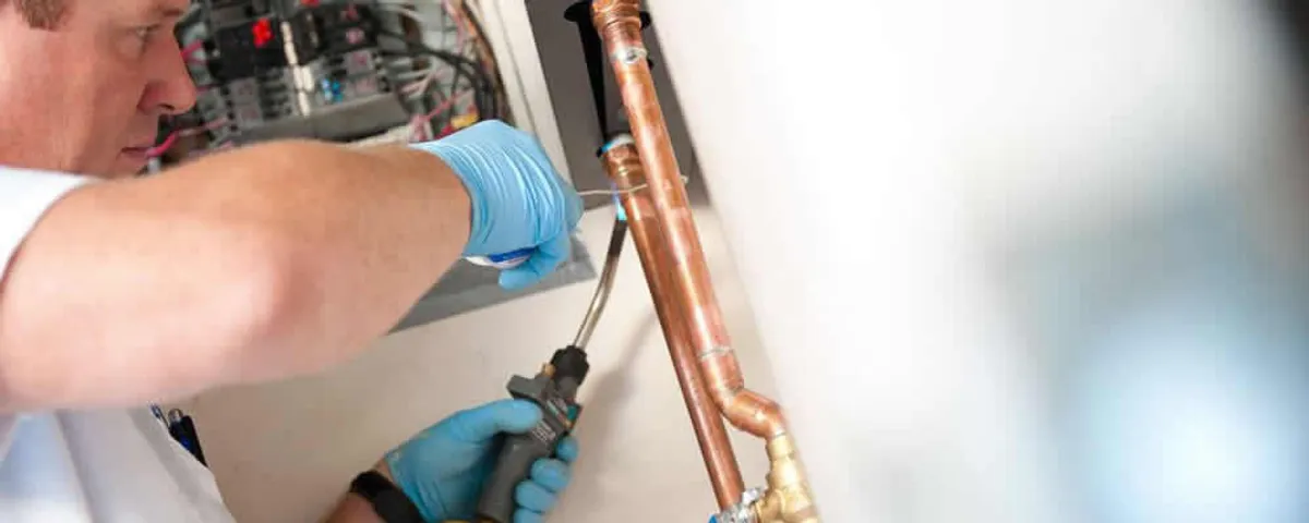 Water heater repair technician testing copper pipe connections and controls in Saint Charles, MO